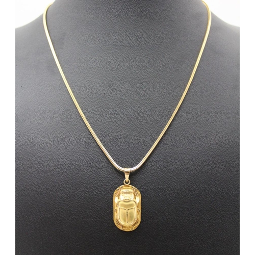 84 - An Egyptian yellow metal pendant with hieroglyph decoration, together with a yellow metal scarab pen... 