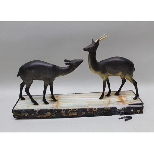 129 - A French Art Deco period figural group of two stylised deer on hardstone plinth, with squashed bun f... 