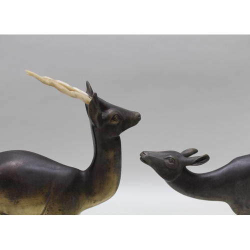 129 - A French Art Deco period figural group of two stylised deer on hardstone plinth, with squashed bun f... 