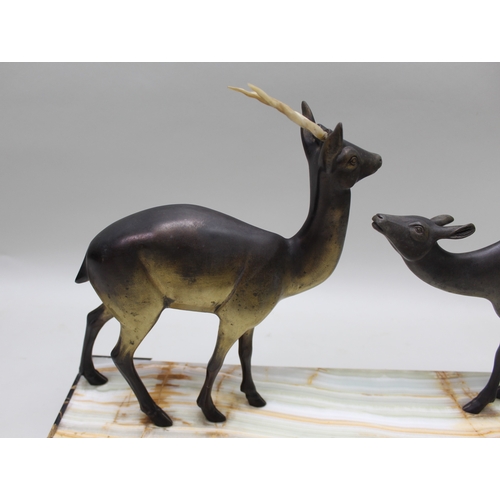 129 - A French Art Deco period figural group of two stylised deer on hardstone plinth, with squashed bun f... 