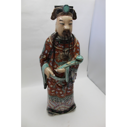 85 - An early 20th century Chinese ceramic Immortal, carrying a Ruyi sceptre, polychrome painted in an el... 