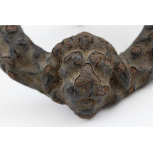 175 - A Victorian cast iron door knocker in the form of a wreath with lion mask, held in a clenched fist, ... 