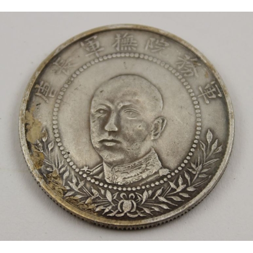 480 - A Chinese silvered coin, a portrait to one side, and crossed flags to the other, 32mm in diameter