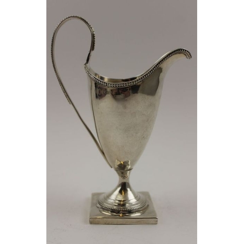 74 - A George III silver helmet form cream jug, beaded rim and high hoop handle, on square platform base,... 