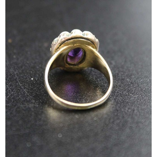 106 - An 18ct gold ring, inset central amethyst cabochon, surrounded by eleven pearls, ring size; 