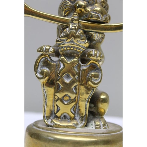 143 - A pair of 19th century Dutch brass twin branch candlesticks, the stem cast as a lion supporting the ... 