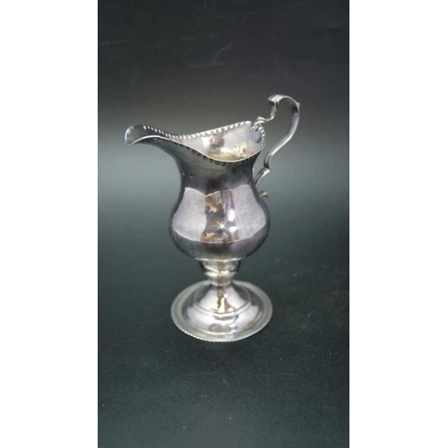 16 - A George III silver cream jug of baluster form with punched rim, C scroll handle and raised circular... 