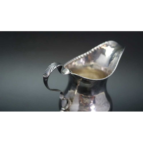 16 - A George III silver cream jug of baluster form with punched rim, C scroll handle and raised circular... 