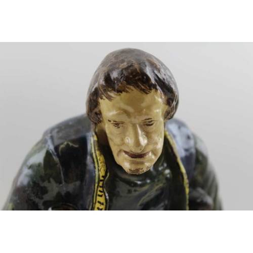 186 - A Continental glazed earthenware figure of a peasant on crutches, c.1900, monogram to base and the n... 