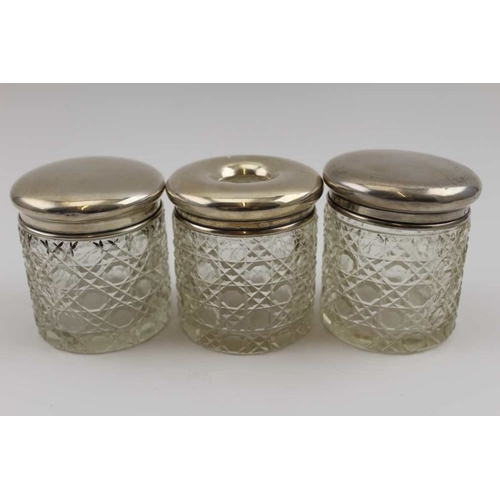 26 - Three silver lidded cut glass dressing table jars, one being a hair tidy (two match Birmingham 1925)... 