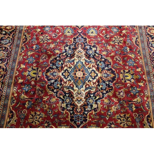 366 - A large Kashan floor carpet, book cover design, central red ground with blue borders, 345cm x 240cm