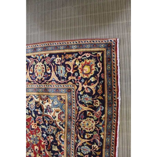 366 - A large Kashan floor carpet, book cover design, central red ground with blue borders, 345cm x 240cm