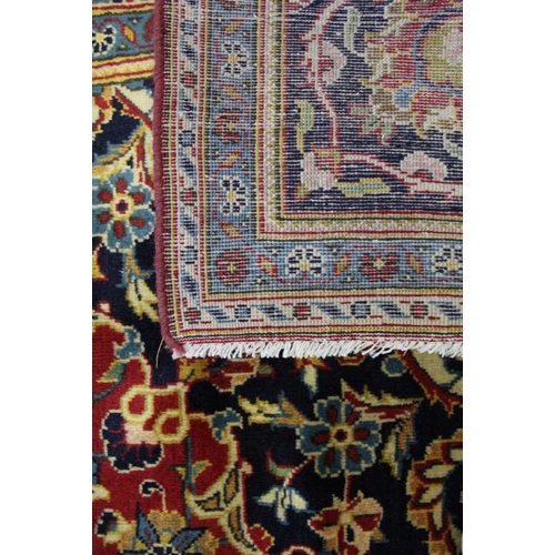 366 - A large Kashan floor carpet, book cover design, central red ground with blue borders, 345cm x 240cm