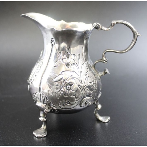 37 - A George II silver cream jug, repousse floral decoration, scroll handle, raised on three trefoil sup... 