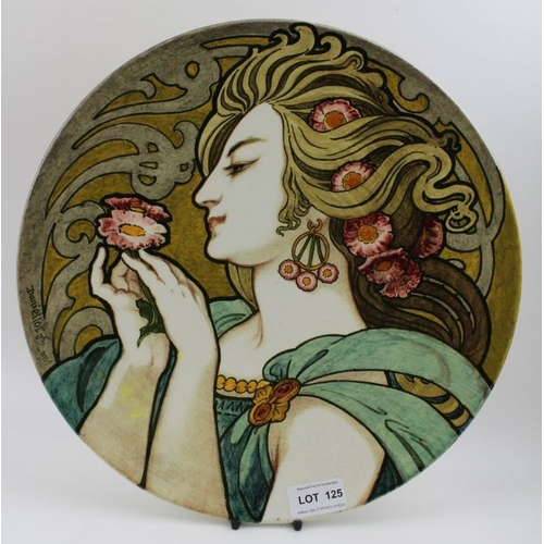 125 - A French Art Nouveau earthenware charger, painted with a young woman in profile admiring a flower, s... 