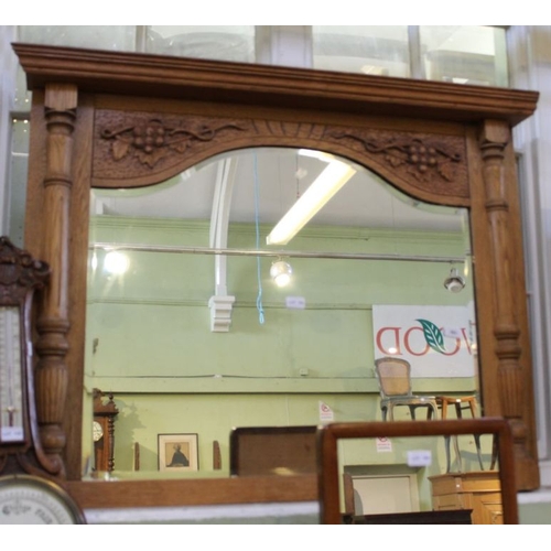 159 - A carved light oak framed arch topped over mantle mirror with grape and vine and half column decorat... 