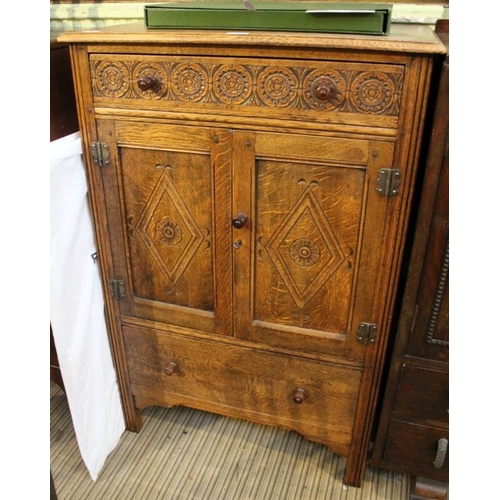 177 - A reproduction oak side cabinet with carved upper drawer over twin panelled cupboard doors and a fur... 