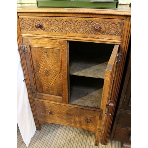 177 - A reproduction oak side cabinet with carved upper drawer over twin panelled cupboard doors and a fur... 