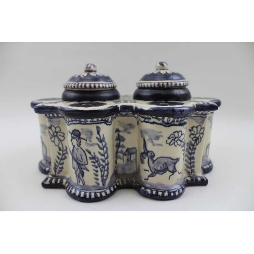 125 - A Continental glazed ceramic desk top inkwell, of fluted form, painted with figures, animals and bir... 