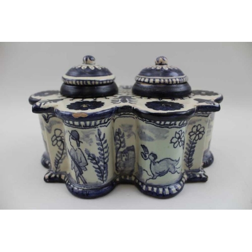 125 - A Continental glazed ceramic desk top inkwell, of fluted form, painted with figures, animals and bir... 