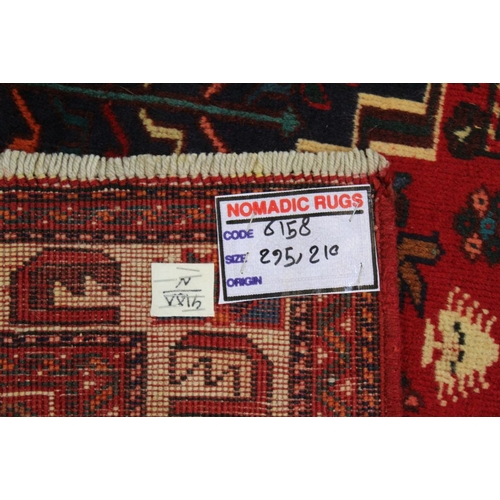 267 - A Persian Shiraz woven woollen carpet, busy blue and red central field 2.95m x 2.10m