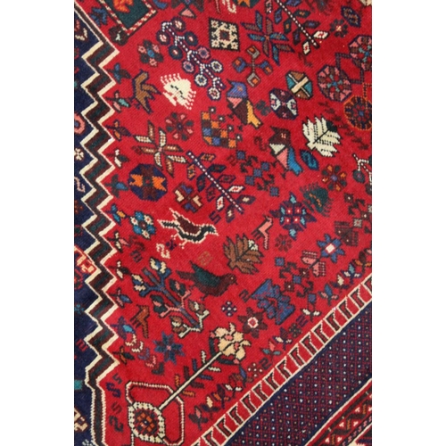 267 - A Persian Shiraz woven woollen carpet, busy blue and red central field 2.95m x 2.10m