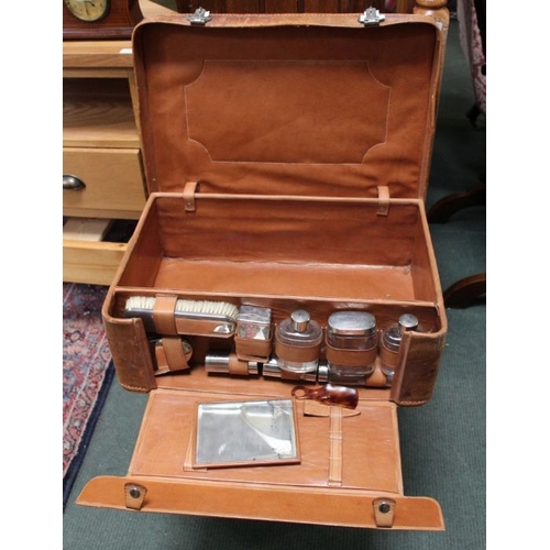 50 - A leather suitcase, having open section revealing fitted vanity items