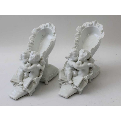 39 - A pair of Continental porcelain ornaments, in the form of Putti in shoes, 14cm