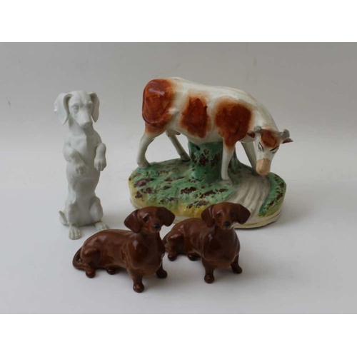 47 - A Victorian Staffordshire pottery cow, 13cm high, together with two Beswick Dachshunds, and a bisque... 