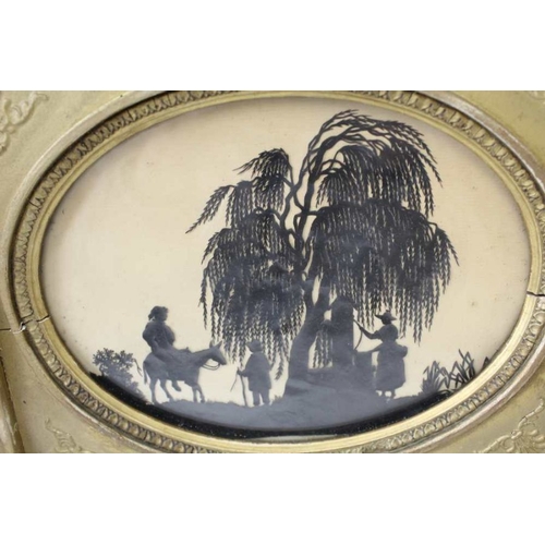 72 - A Regency cut out silhouette depicts figures at a well, 15cm x 20cm, oval mounted, in a gilt frame