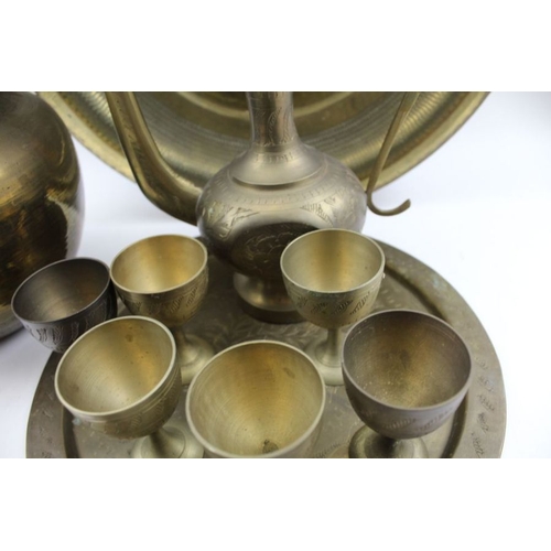 96 - A collection of Middle Eastern brassware, includes a coffee set with pot and cups on tray, together ... 