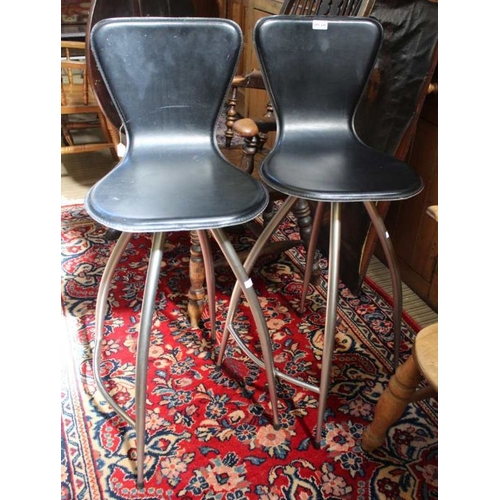 235 - A pair of bar stools, black leather upholstered, swivelling on four leg metal bases