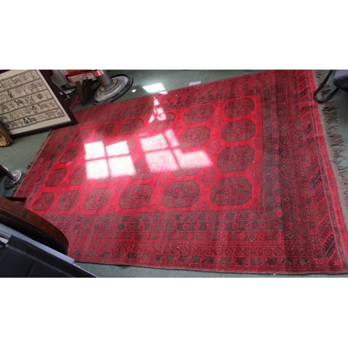 176 - A large sized woven woolen floor carpet of red ground, with multiple central elephants feet, within ... 