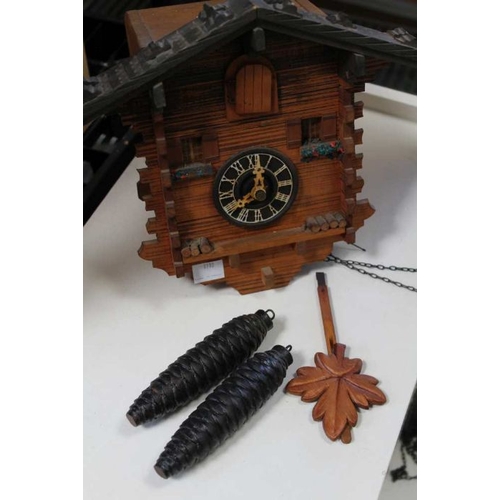 223 - A traditional wooden Cuckoo clock, with pendulum and pine cone weights