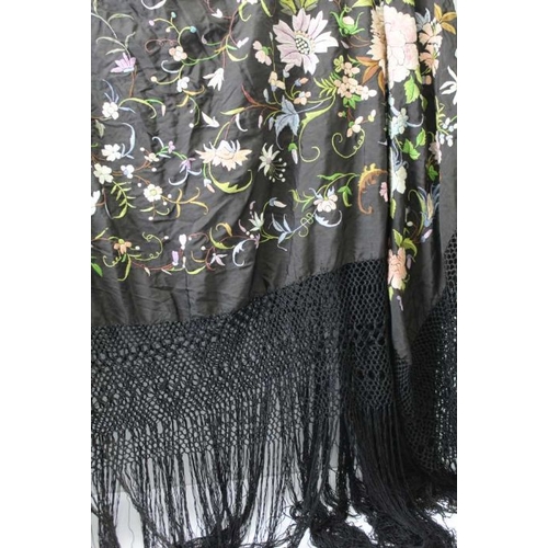 148 - A late 19th century shawl, the black ground embroidered all over with flowers in multi-colours, with... 