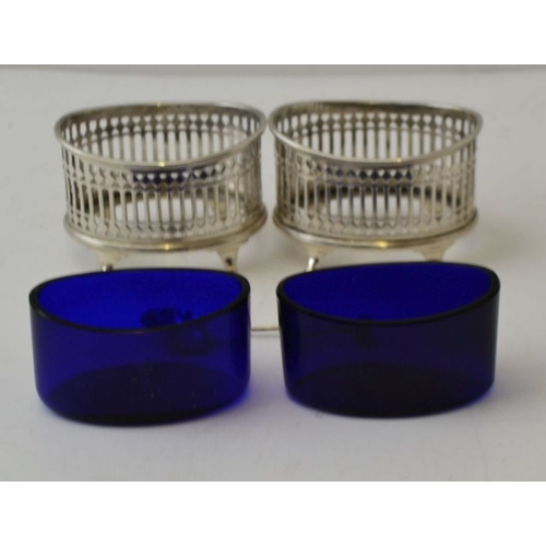 67 - Stokes & Ireland Ltd. A pair of Edwardian pierced silver salts, London 1904, with blue glass liners ... 