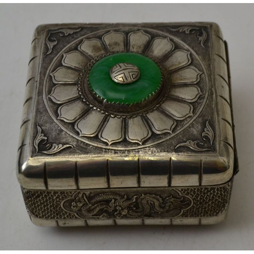 82 - An Oriental white metal lidded box, with embossed dragon motifs, the lid inset jade roundel, 7cm squ... 