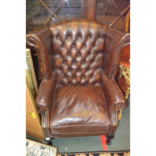 122 - A reproduction Georgian design wingback armchair upholstered in distressed chocolate brown leatheret... 