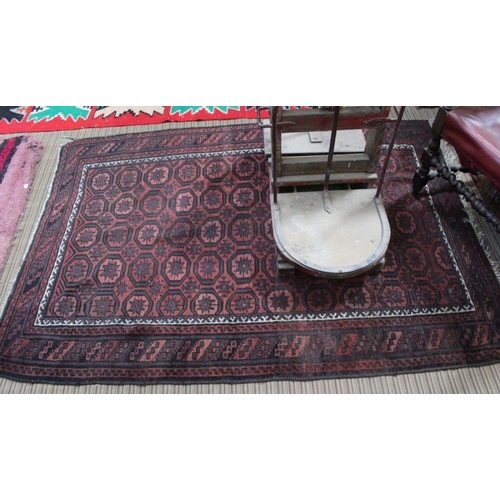 172 - A woven woollen red ground floor rug with star patterned central field 132 x 190 cm