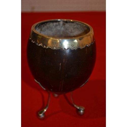 26 - A George III coconut cup with white metal rim on three white metal supports 14 cm high