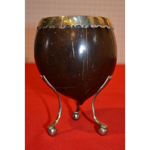 26 - A George III coconut cup with white metal rim on three white metal supports 14 cm high