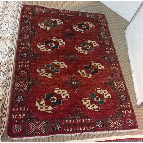 99 - A red ground Turkoman rug, styled motifs in cream and blue, fringed 178cm x 127cm