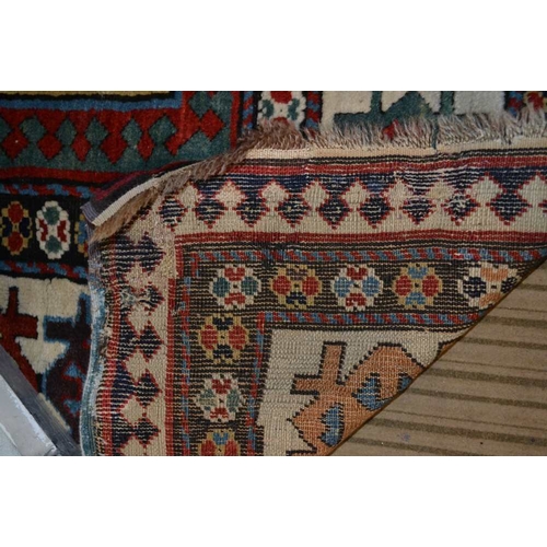 96 - An antique Kazak long rug, having narrow plain central blue panel, within a framework of borders in ... 