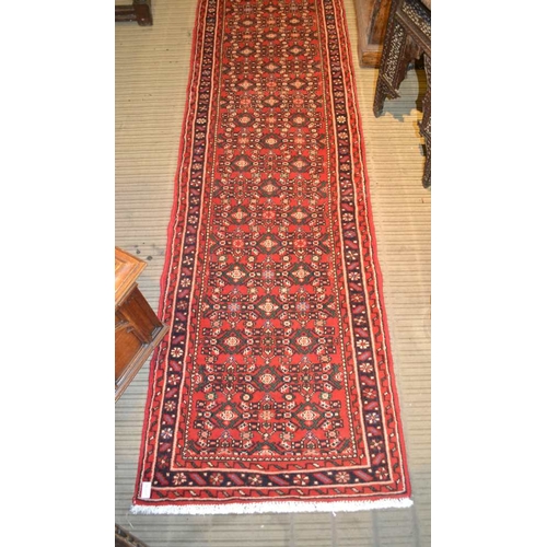 98 - A Persian Hosseinabad runner, red ground, geometric design, fringed and bordered, 772cm x 70cm