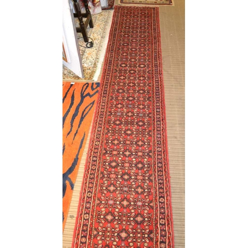 98 - A Persian Hosseinabad runner, red ground, geometric design, fringed and bordered, 772cm x 70cm