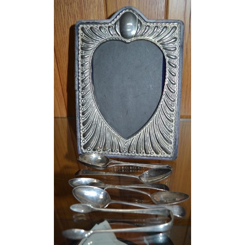 180 - A silver plated photograph frame, together with hallmarked silver spoons, sugar nips, and one other ... 