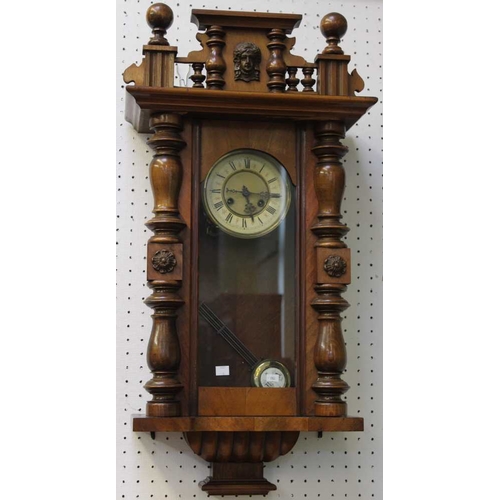 42 - A Vienna wall clock, polished wood case with turnings and mask to the crest, 82cm high