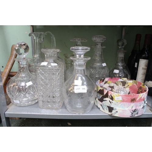 346 - A shelf containing a wide selection of cut glass and other decanters with spare stoppers