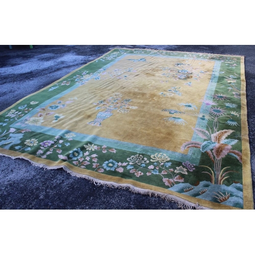 366 - A roomsize Chinese carpet, golden ground with vase of flowers decoration. Green floral border 460cm ... 