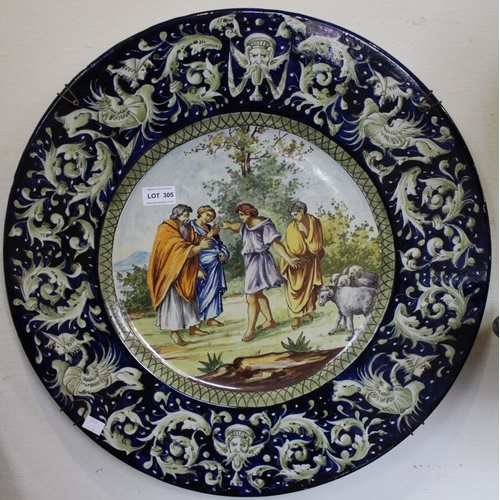 305 - A Continental Majolica wall charger, classical scene to the centre, figures at a well, bordered by a... 